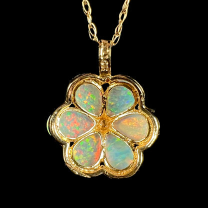 Back side of gold lab-creaed opal flower pendant shown on chain; the pendant's fixed bail has a "14K" hallmark stamp