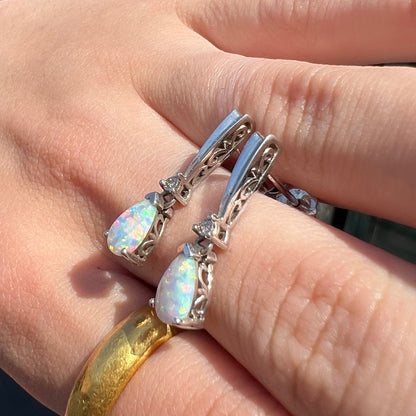 A pair of sterling silver filigree dangle earrings mounted with pear shaped lab created opals and diamond accents.