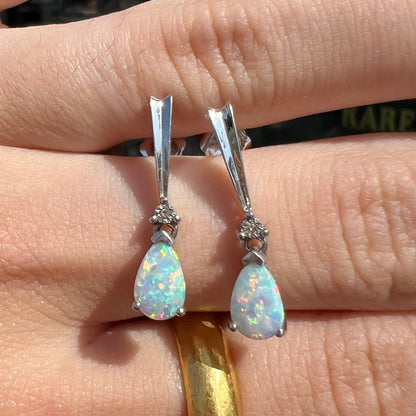 A pair of sterling silver filigree dangle earrings mounted with pear shaped lab created opals and diamond accents.