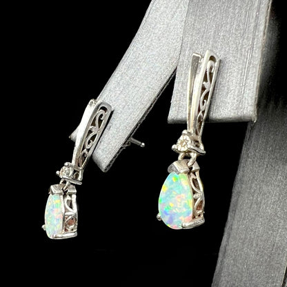 A pair of sterling silver filigree dangle earrings mounted with pear shaped lab created opals and diamond accents.