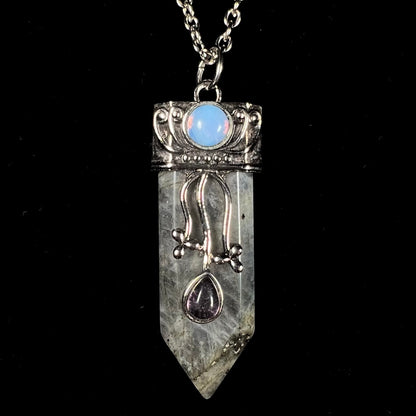 A stainless steal necklace set with a crystal shaped labradorite stone, purple glass, and an opalite accent.