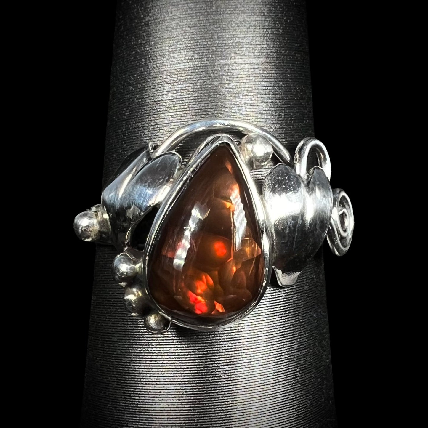 A ladies' pear shaped red fire agate ring with a sterling silver leaf design shown from the front.