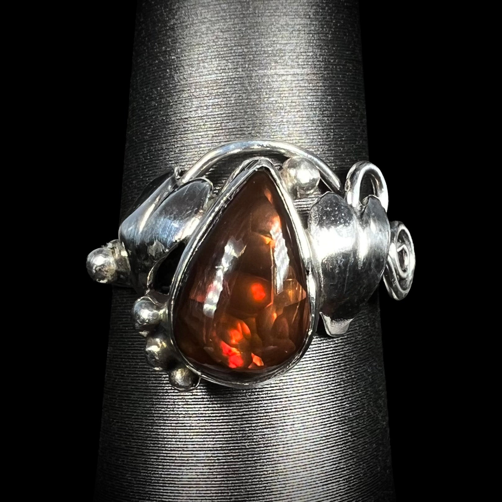 A ladies' pear shaped red fire agate ring with a sterling silver leaf design shown from the front.