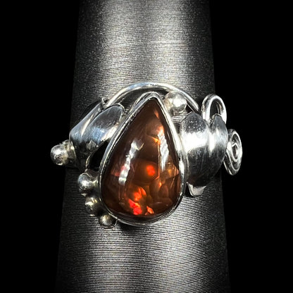 A ladies' pear shaped red fire agate ring with a sterling silver leaf design shown from the front.