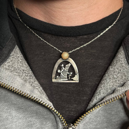 A ladies' sterling silver Ethiopian opal wolf and cat design necklace, worn around a neck against a dark shirt.