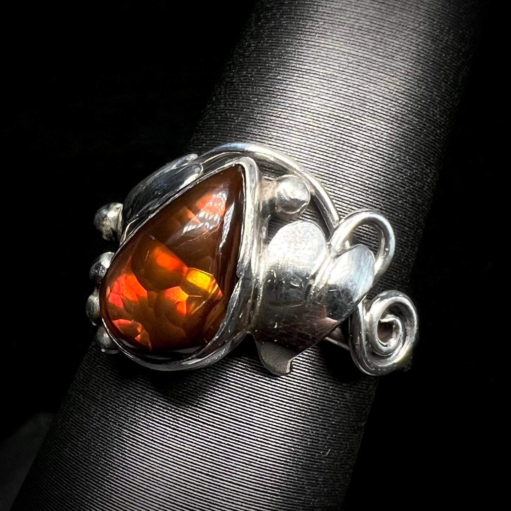 A ladies' pear shaped red fire agate ring with a sterling silver leaf design shown from an angle.