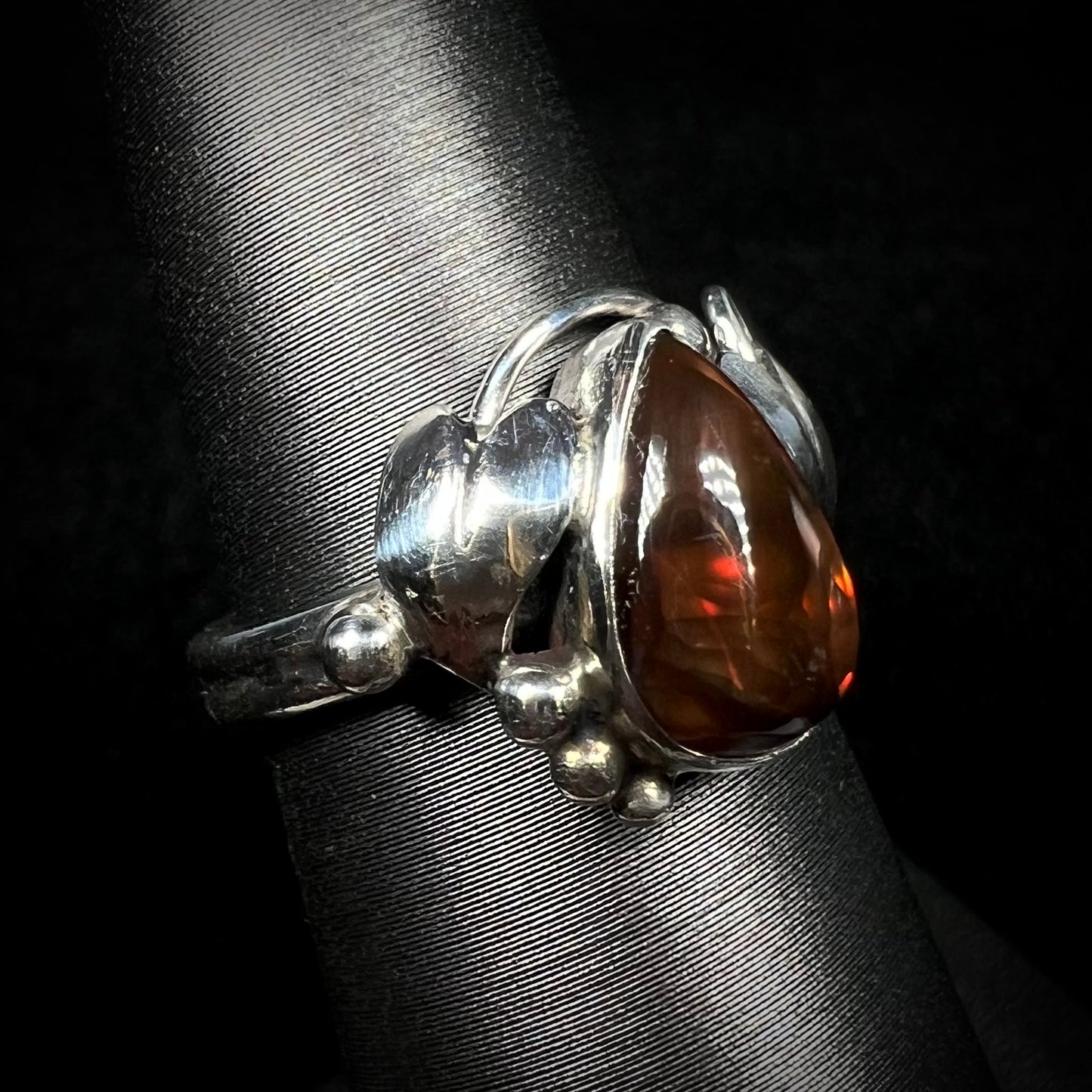 Angled view of a ladies' pear shaped red fire agate ring with a sterling silver leaf design.