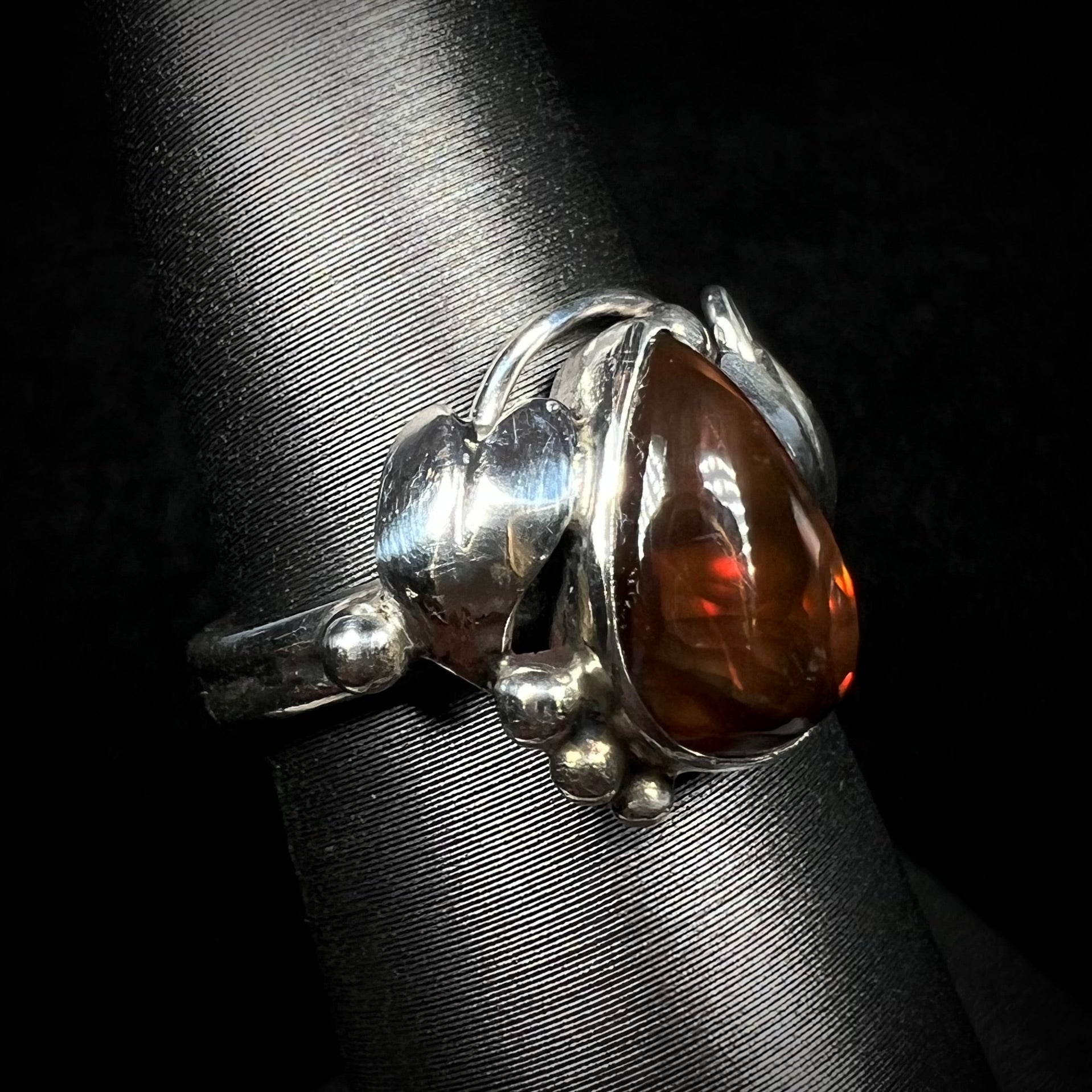 Angled view of a ladies' pear shaped red fire agate ring with a sterling silver leaf design.