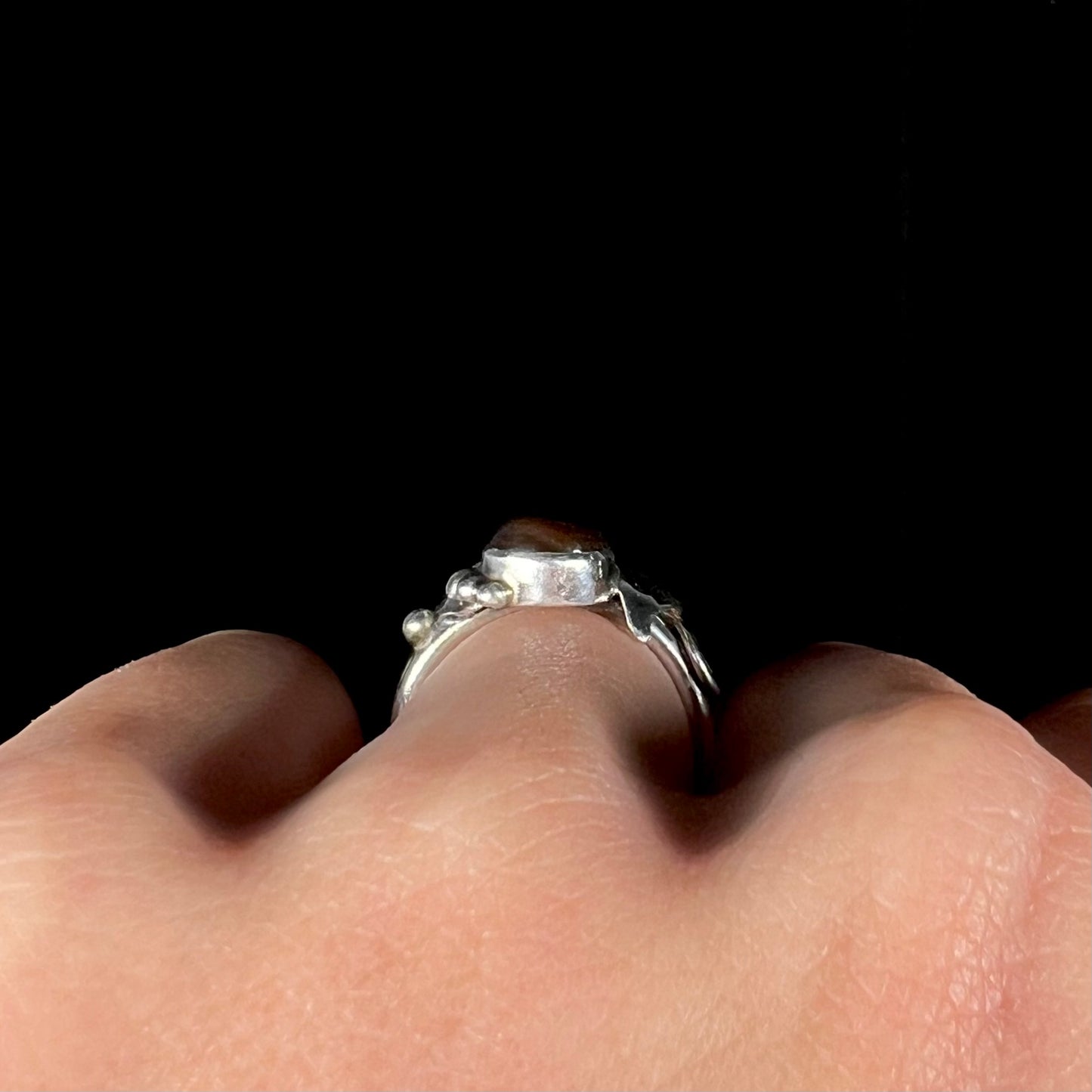 Side profile gallery view of a ladies' silver fire agate ring worn on a hand.
