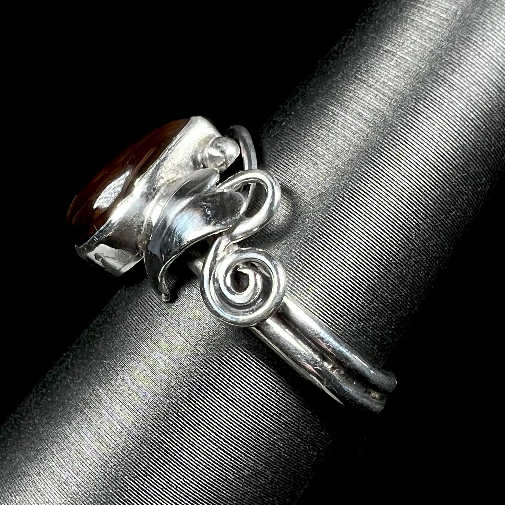 Side view of a ladies' silver fire agate ring with a vine and leaf design.