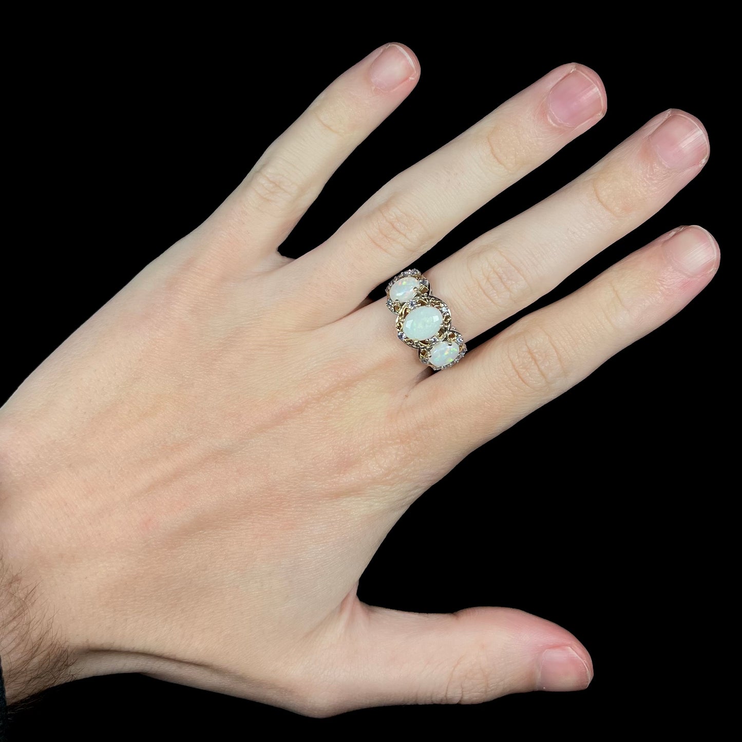 Hand wearing a ladies' sterling silver three-stone Australian white opal and tanzanite-accented ring.