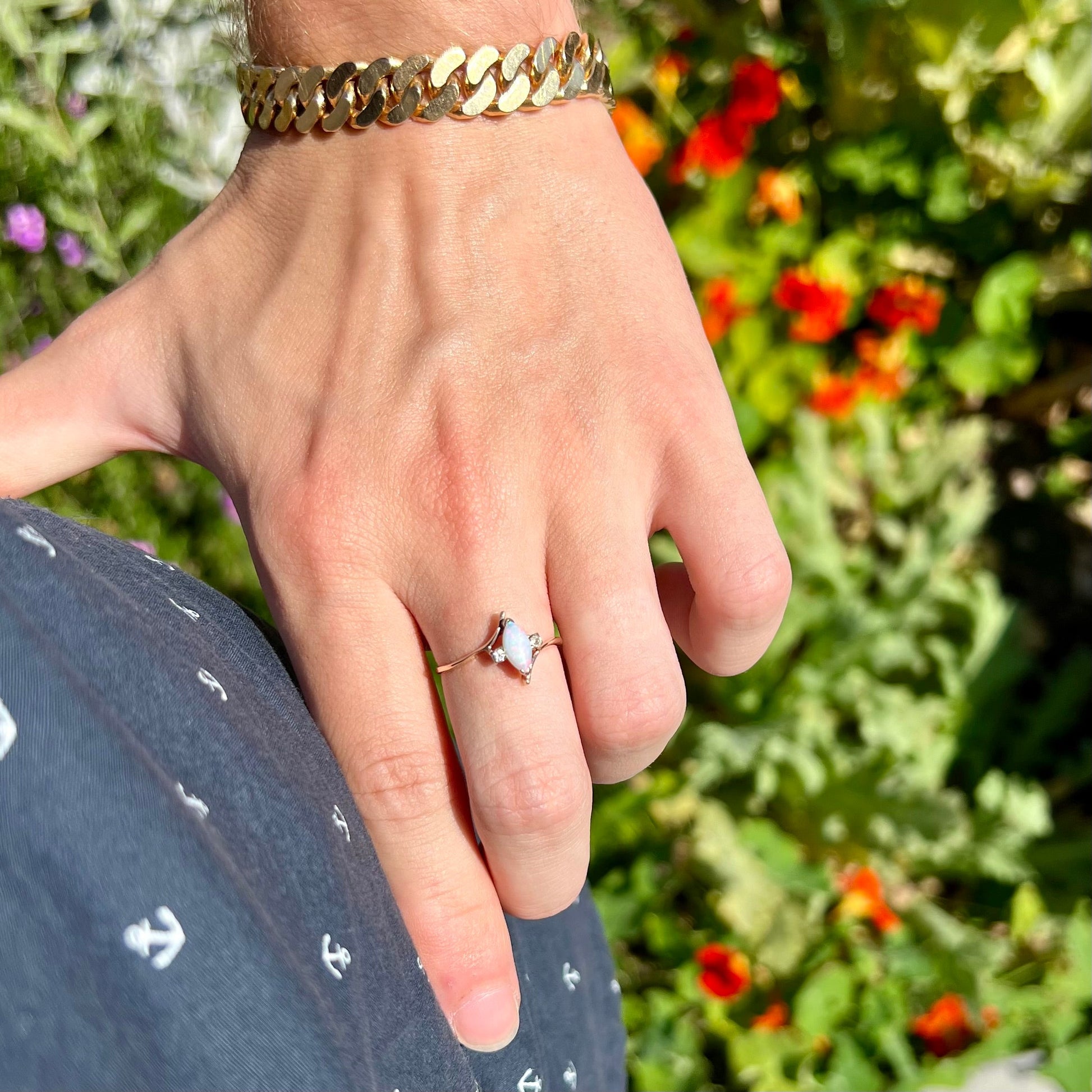 A yellow gold marquise cut opal ring set with two white sapphire accent stones.