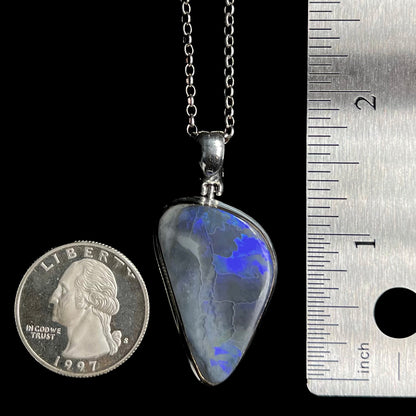 Large-sized black opal pendant measuring 1.8" long from top of silver bail, shown between US quarter coin and ruler