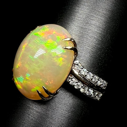 Angled close-up of large double-prong style Ethiopian opal and diamond pave ring on display
