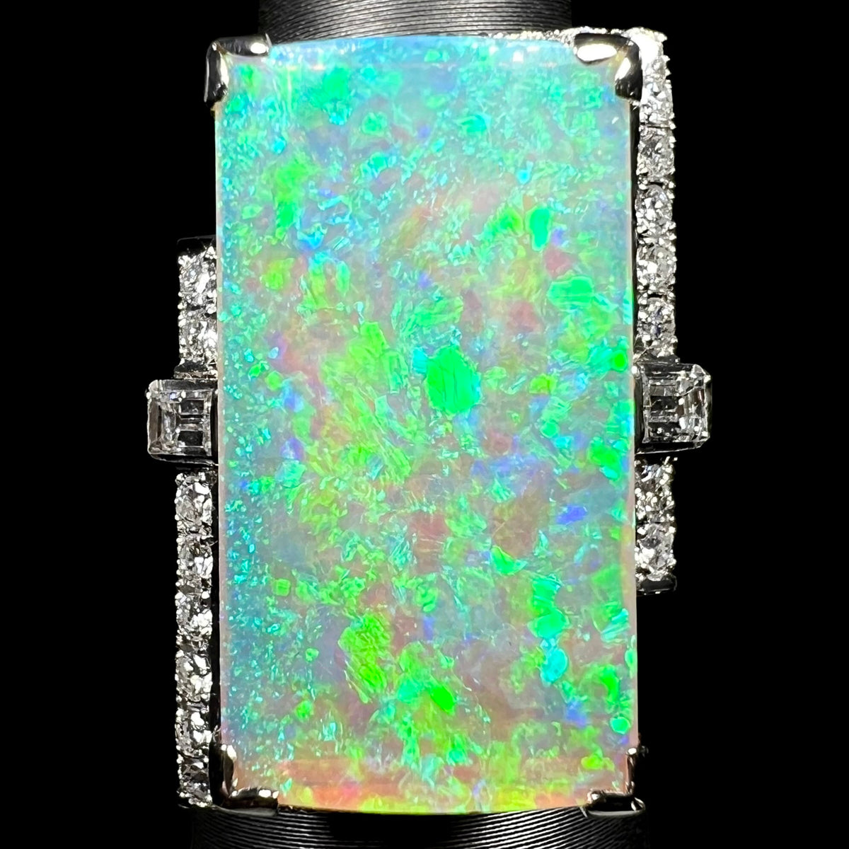 Large rectangular Australian light opal and diamond cocktail ring in vintage Japanese platinum, with vivid green-dominant play-of-color across the 11.46ct center stone under LED studio light.