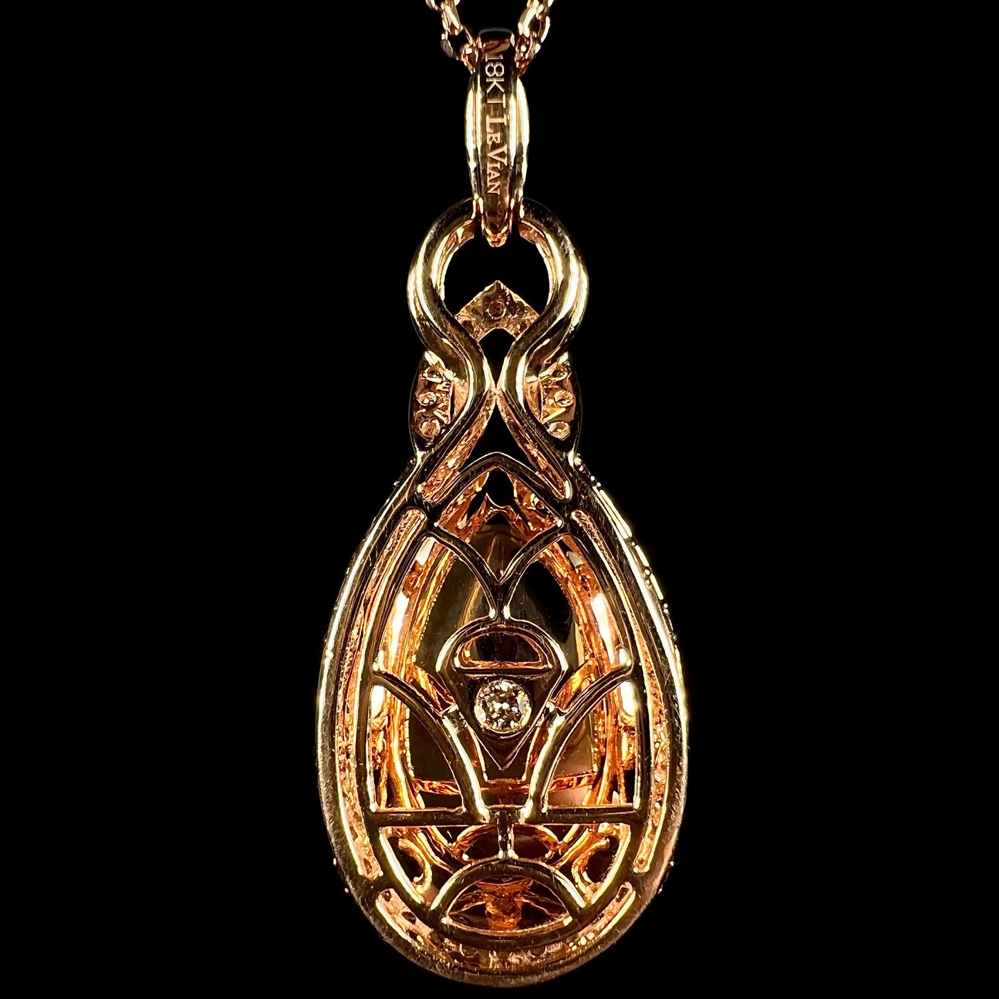 Back side of a Le Vian-designed 18k rose gold pendant, shown against a black backdrop.  A single diamond is seen set in the middle of the pendant.