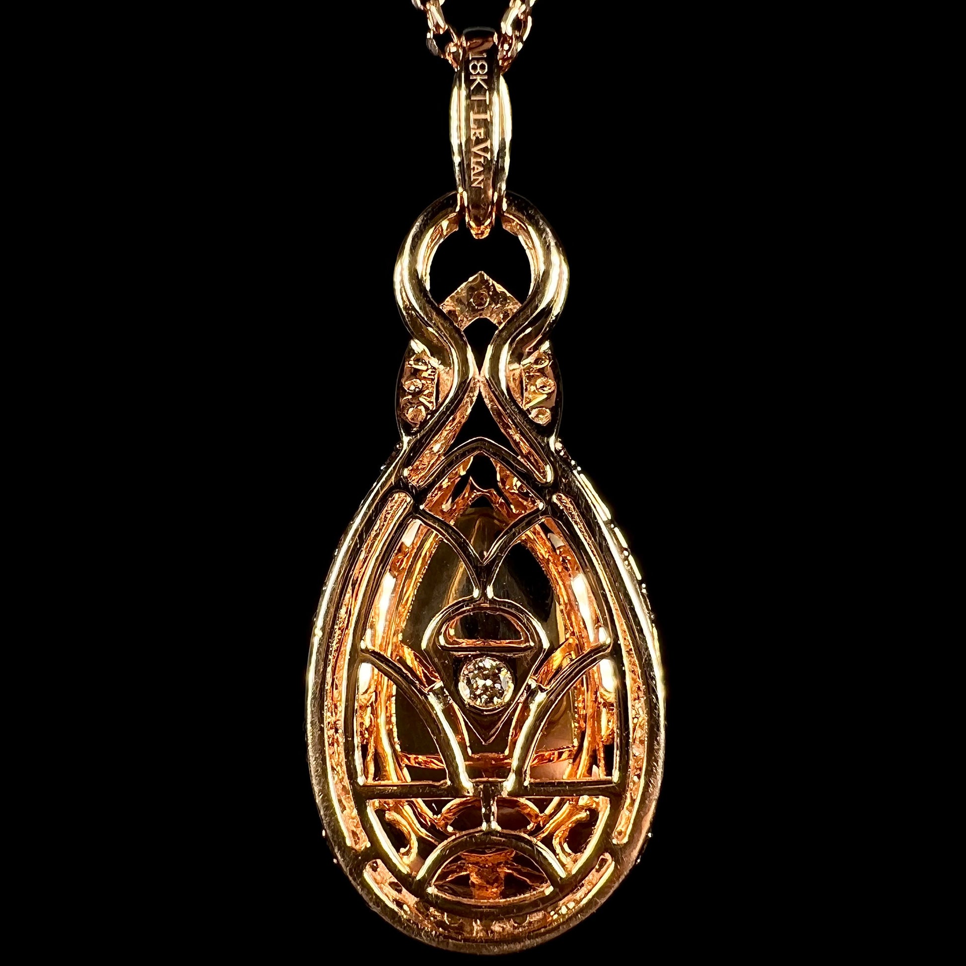Back side of a Le Vian-designed 18k rose gold pendant, shown against a black backdrop.  A single diamond is seen set in the middle of the pendant.