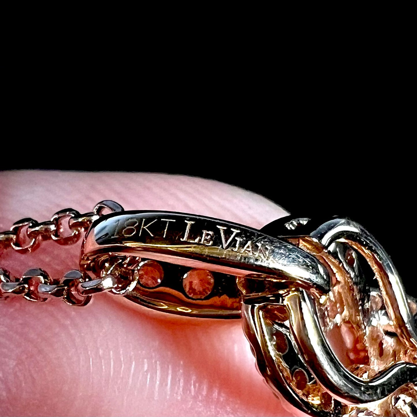 Close-up macro shot of the back of a rose gold pendant's bail, focused on the hallmark stamp "18KT LE VIAN".