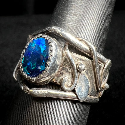 Angled close-up of wrapping leaf and vine design along the shank of sterling silver black opal doublet ring, shown on display