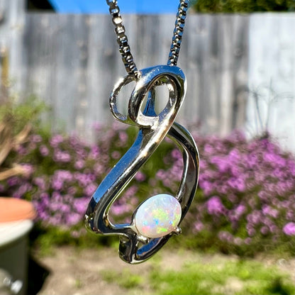 A ladies' sterling silver necklace set with an oval cabochon cut natural white crystal opal with green fire.