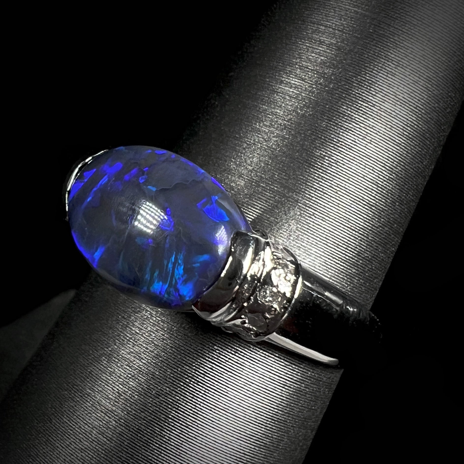 A Lightning Ridge black opal platinum ring.  The ring has diamond accents.