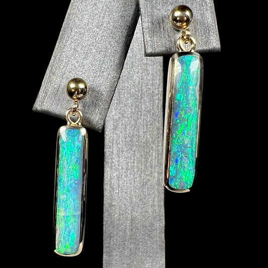 A pair of Lightning Ridge opal drop earrings made from yellow gold, shown from the front.