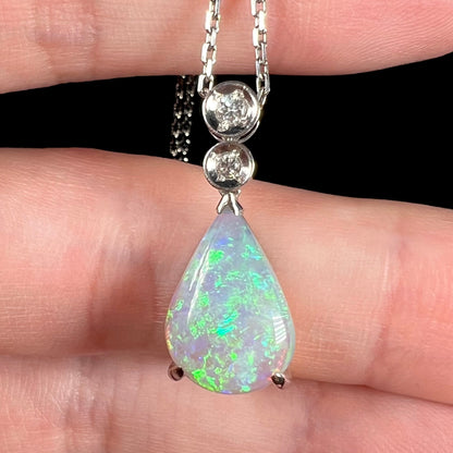 A platinum drop pendant mounted with two diamond accents and a pear shaped green-blue crystal opal.