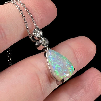 A platinum drop pendant mounted with two diamond accents and a pear shaped green-blue crystal opal.