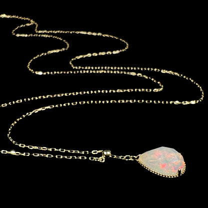 Artistic shot of the long-chain opal necklace lying on a black background, displaying its wavy, fluid design.