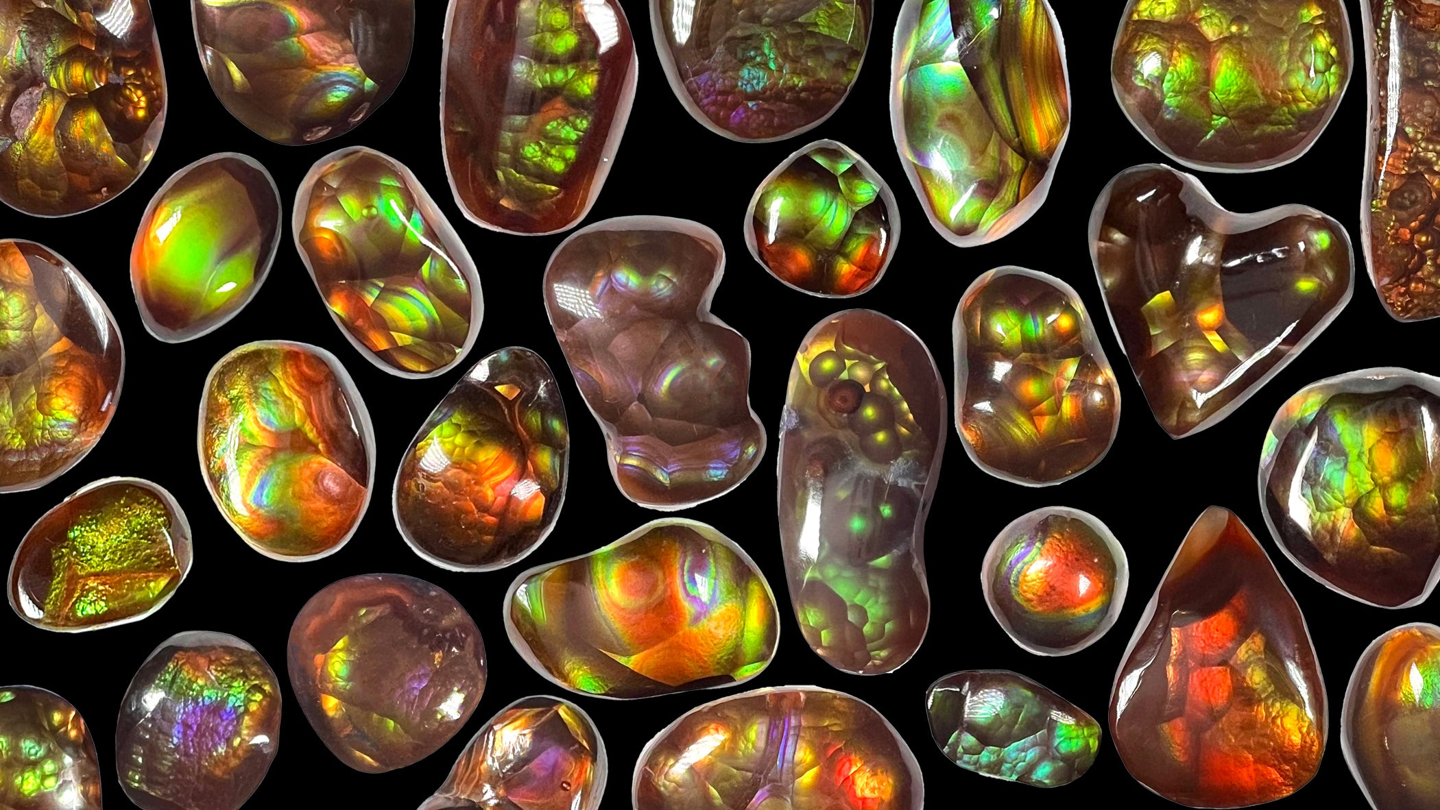 Different shaped Mexican fire agate cabochons arranged on a black background.