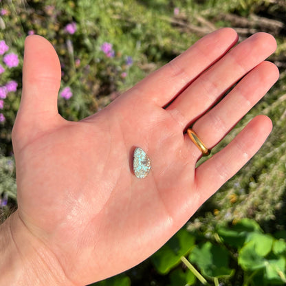 A loose, freeform cabochon cut Valley Blue turquoise stone.  The stone is light blue with black and brown matrix.