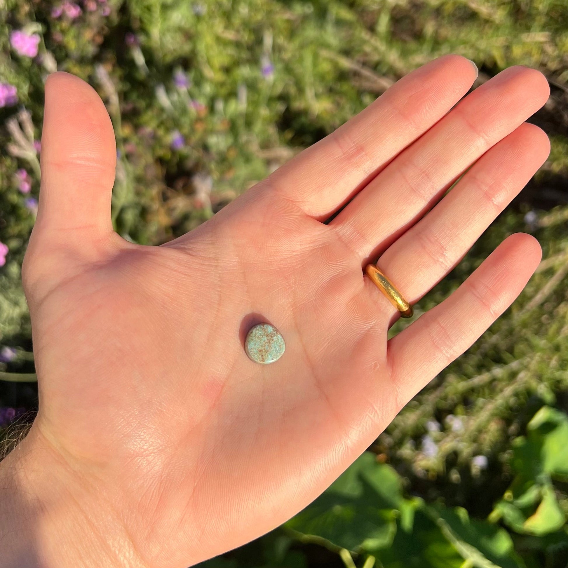 A loose, off-round cabochon cut turquoise stone.  The stone is light blue with a red webbed matrix.