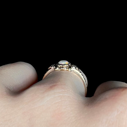 Antique 9k gold opal ring viewed from side profile gallery on hand, its low-profile bezel set design visible
