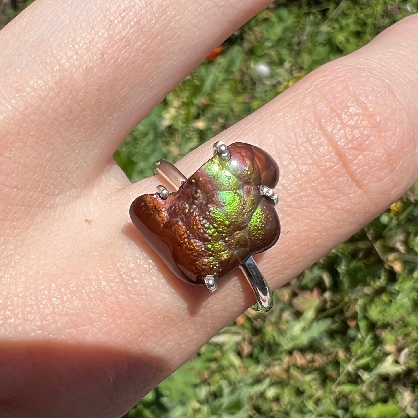 Macro outdoor shot of fire agate ring showing green and purple iridescence.