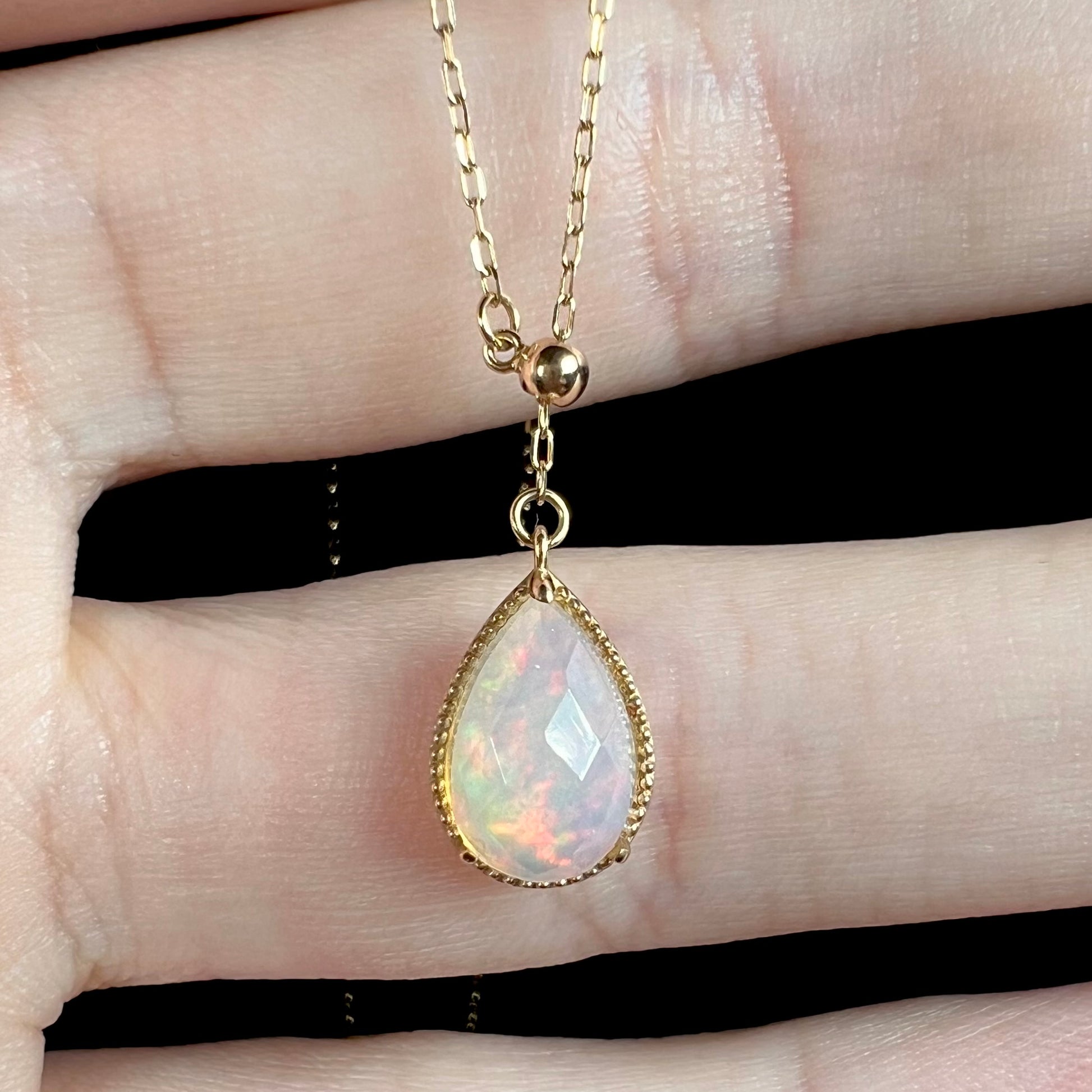 Macro view of the faceted opal pendant, highlighting subtle red flashes and sparkling facets.