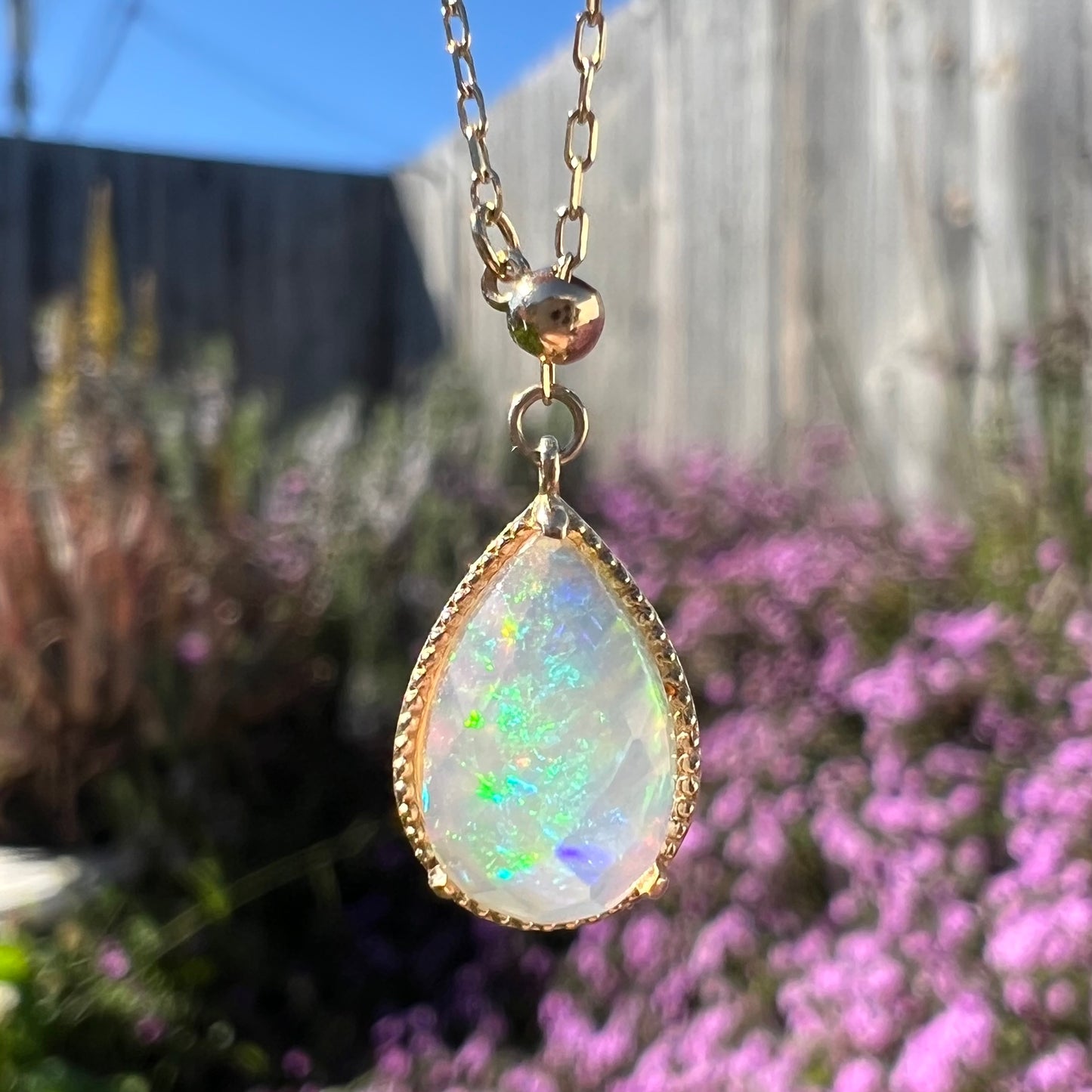 Macro outdoor view of the opal necklace without a hand, showing green and blue flashes more prominently.