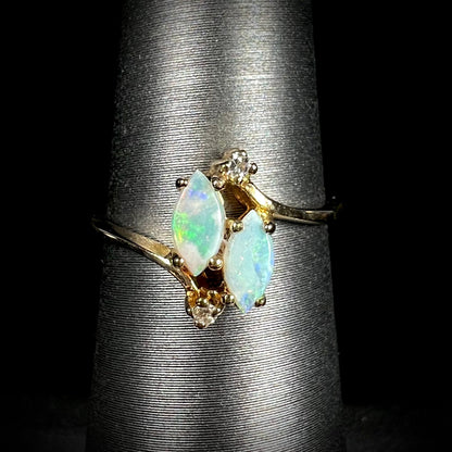 A ladies' gold ring mounted with two marquise cut opals and two diamond accents.