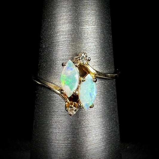A ladies' gold ring mounted with two marquise cut opals and two diamond accents.