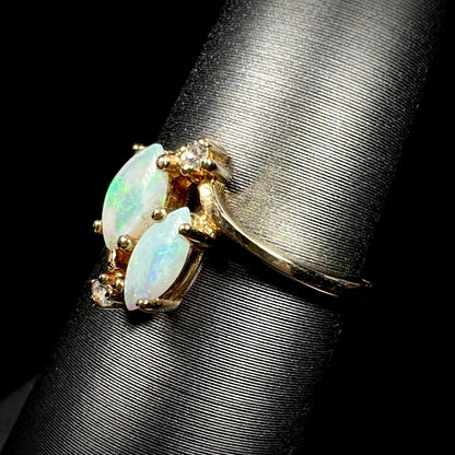 A ladies' gold ring mounted with two marquise cut opals and two diamond accents.