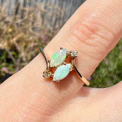 A ladies' gold ring mounted with two marquise cut opals and two diamond accents.