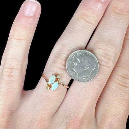 A ladies' gold ring mounted with two marquise cut opals and two diamond accents.