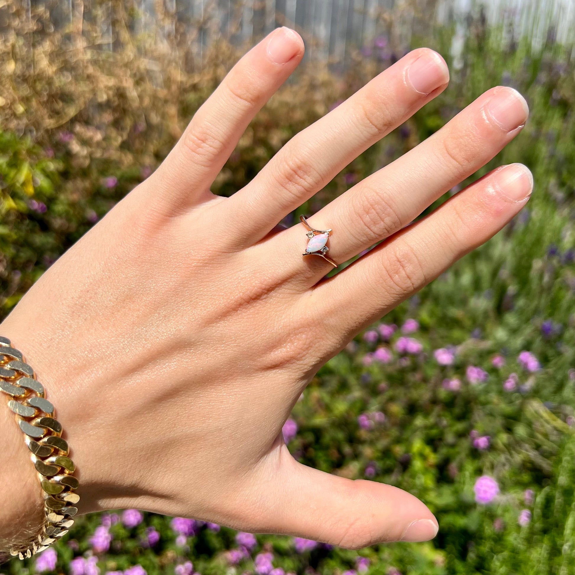 A yellow gold marquise cut opal ring set with two white sapphire accent stones.