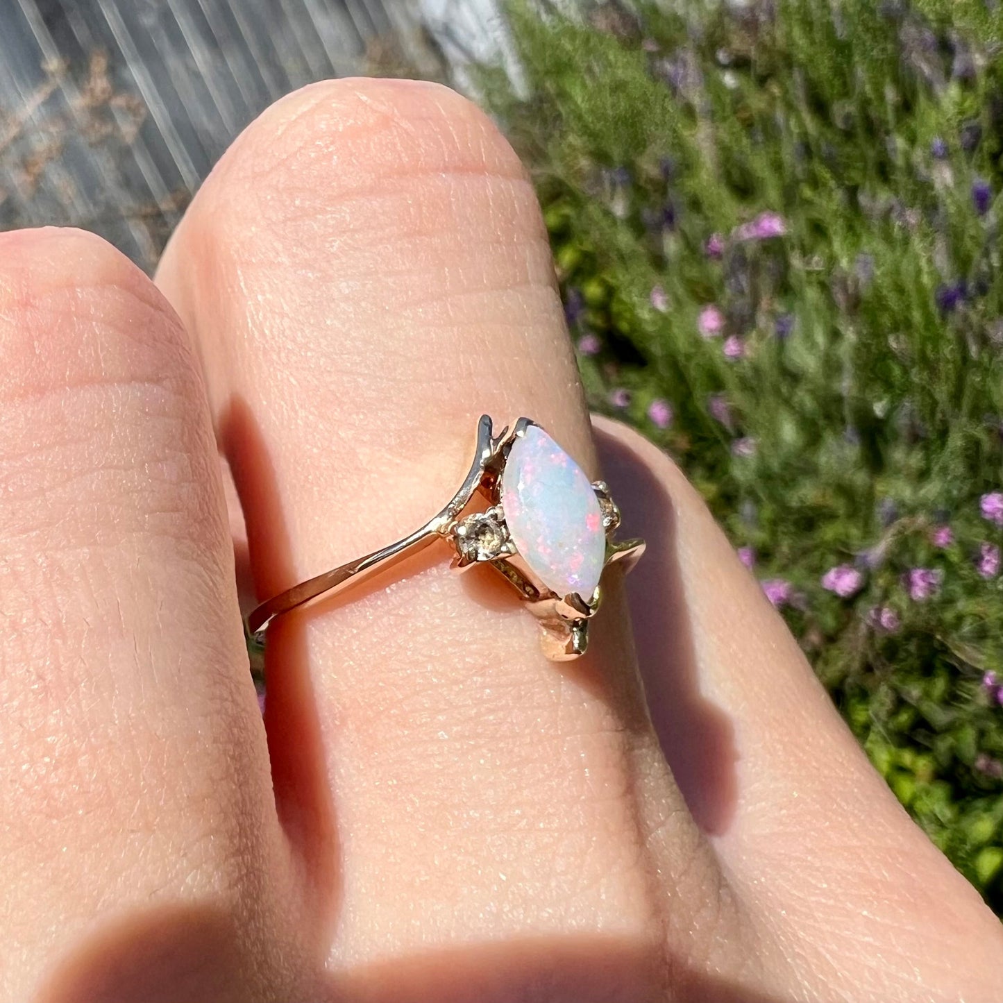 A yellow gold marquise cut opal ring set with two white sapphire accent stones.