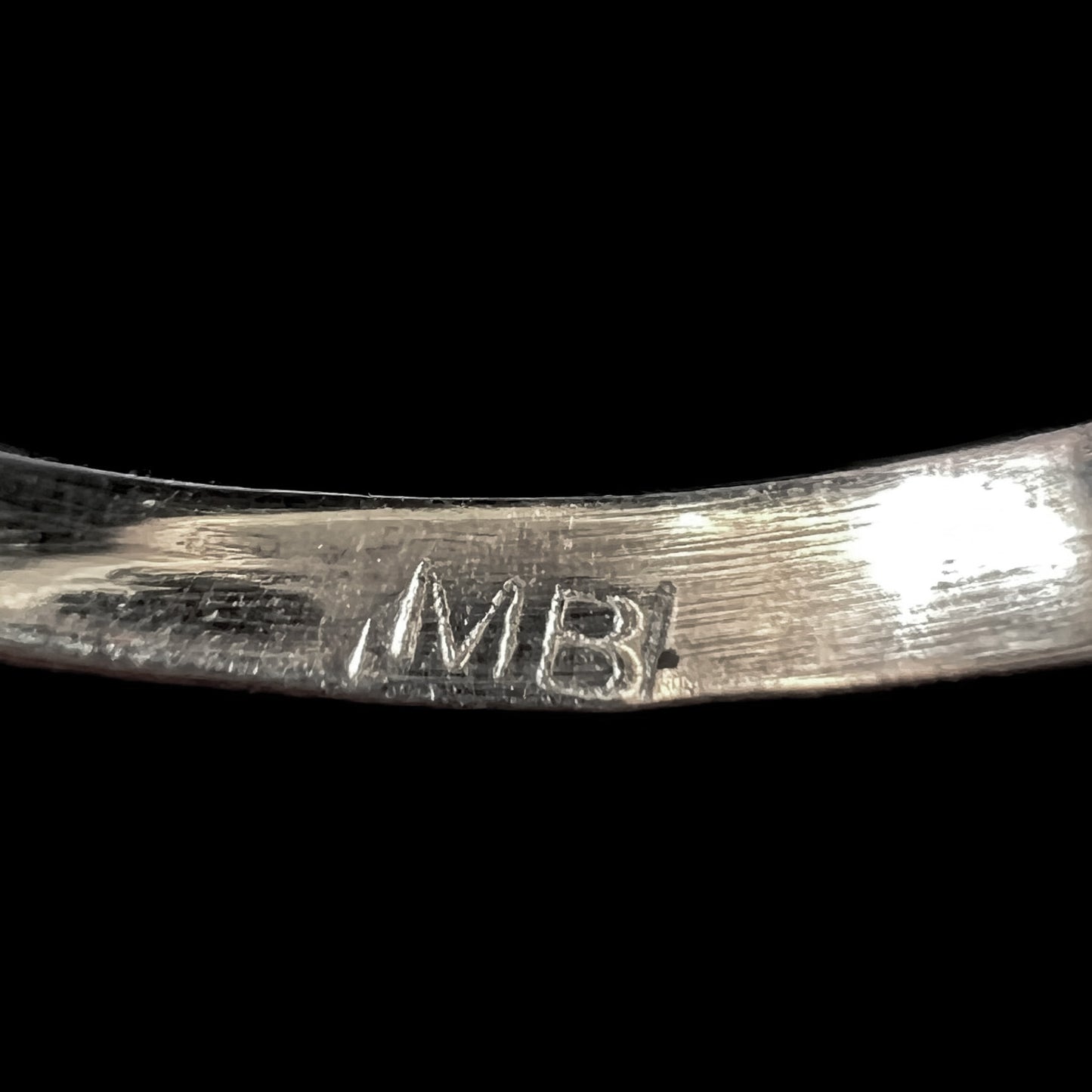 The inside of a silver ring's shank stamped with the initials, "MBI"