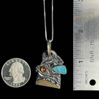 A 1.6 inch-long men's Australian opal doublet and amber pendant, shown next to a ruler and US quarter coin for scale.