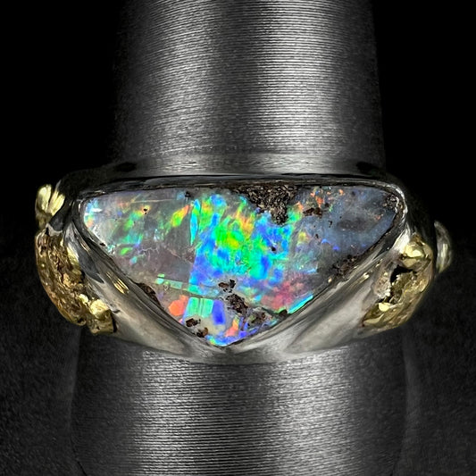 A men's Australian boulder opal ring in sterling silver with gold nugget accents shown close-up from the front on a ring display.