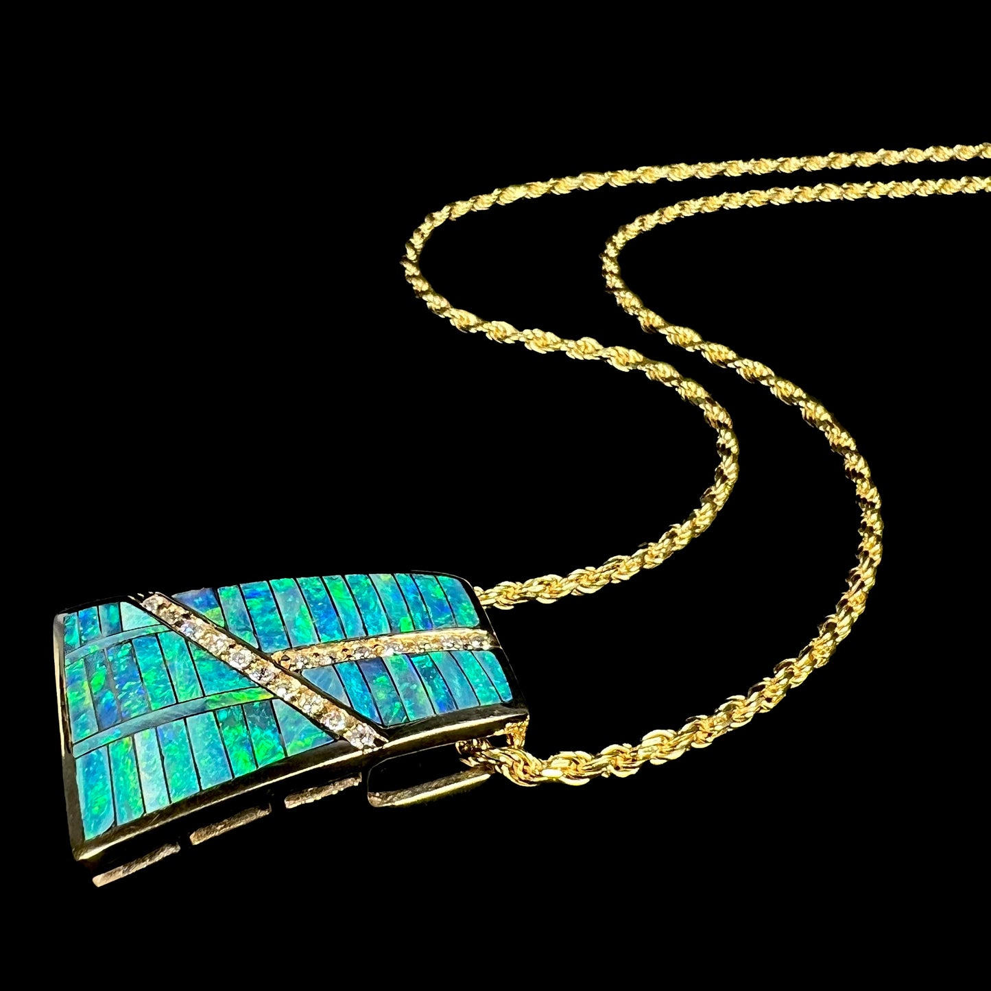 Angled view of a gold men's Australian opal inlay necklace laying against a black background.
