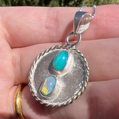 Close-up macro angled view of a men's Australian opal necklace made from sterling silver, shown held in natural light.