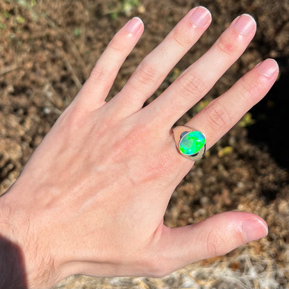 Hand wearing green crystal opal men's ring in sunlight