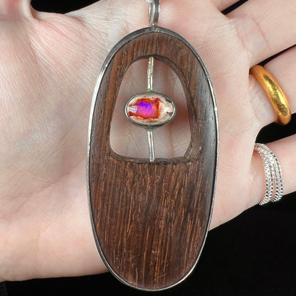 Close-up front view of a handmade men's Mexican fire opal and brown wood pendant.  The opal has subtle purple play of color over its orange body.